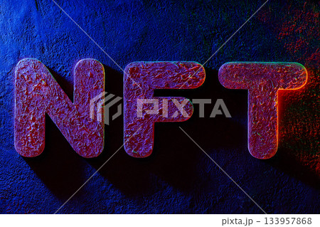 NFT Letters Illuminated by Neon Lighting on Textured Surface 133957868