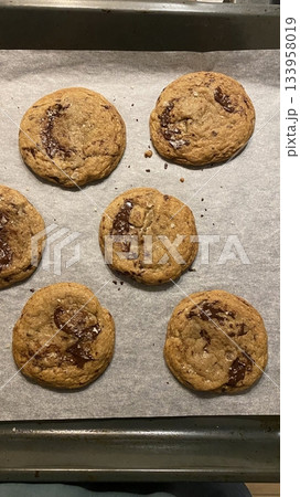 Freshly baked cookies with a golden-brown finish and chocolate chips. Perfectly crisp on the edges with a soft center, offering a delicious, comforting treat for any occasion. 133958019