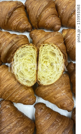 A croissant is a classic French pastry known for its buttery, flaky layers and golden crust. Often enjoyed plain or filled with chocolate, almond, or ham and cheese, it’s a perfect for breakfast 133958368