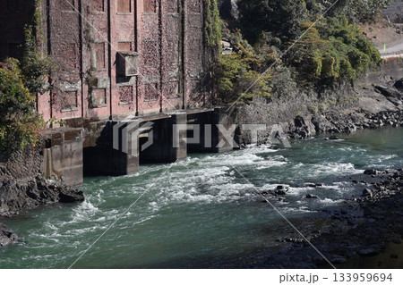 流れの早い川とレンガ造りの建物と木々のある風景 133959694