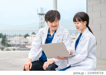 病院の屋上で話す医者・医師・医療従事者・ドクター・薬剤師・科学者・研究員の男女 133959719