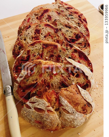 Sourdough bread with golden brown crust and rustic texture, sliced to reveal soft airy crumb inside, highlighting its natural shape, crisp surface, and artisanal detail in close-up view 133959966