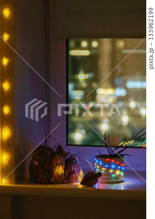 Festive string lights glowing on windowsill at night. 133962199
