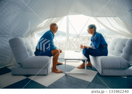 グランピング施設でくつろぐシニア夫婦の会話シーン 133962240