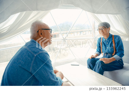 グランピング施設でくつろぐシニア夫婦の会話シーン 133962245