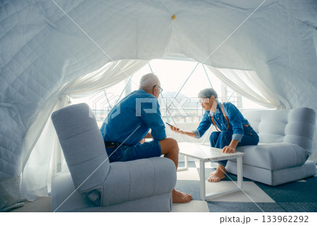 グランピング施設でスマホ撮影を楽しむシニア夫婦 133962292