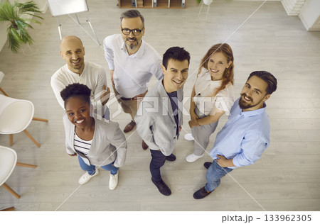 Team of happy multiracial business colleagues smiling together looking up in office. Team of happy multiracial business colleagues smiling together looking up in office. 133962305