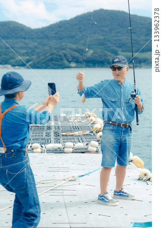 釣れた魚を記念撮影するシニア夫婦 133962378