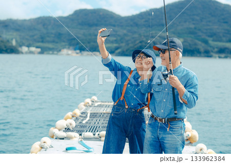 釣れた魚を記念撮影するシニア夫婦 133962384