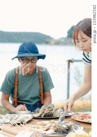 湖畔で親子3人がBBQを楽しむシーン 133962582