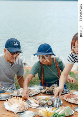 湖畔で親子3人がBBQを楽しむシーン 133962583