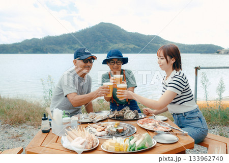 海辺で親子三人の乾杯シーン 133962740