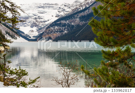 Tranquil Lake Louise with reflecting snow-capped mountain peaks and glacial slopes in crystal clear turquoise water in Banff National Park, Canada 133962817