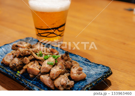 焼き鳥とビールを楽しむ晩酌の時間、木のテーブルに並ぶ和風おつまみ 焼き鳥とビールを楽しむ晩酌の時間、木のテーブルに並ぶ和風おつまみ 133963460