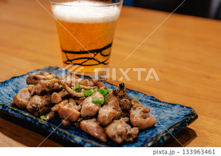 焼き鳥とビールを楽しむ晩酌の時間、木のテーブルに並ぶ和風おつまみ 133963461