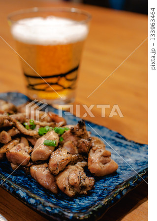 焼き鳥とビールを楽しむ晩酌の時間、木のテーブルに並ぶ和風おつまみ 焼き鳥とビールを楽しむ晩酌の時間、木のテーブルに並ぶ和風おつまみ 133963464