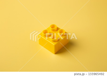 Yellow plastic toy block on monochrome background 133965492
