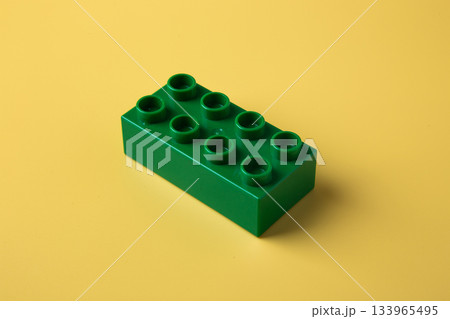 Green lego plastic toy block on yellow background 133965495
