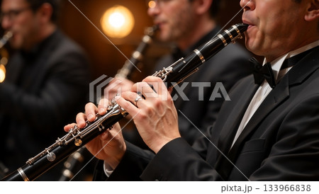 Close-up of a clarinetist playing in a symphony orchestra. Professional musician in a tuxedo performing at a classical music concert 133966838