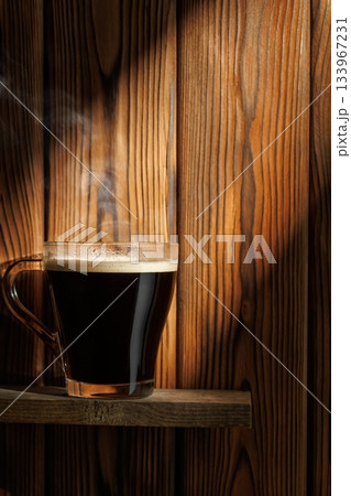 Ray of light falls on transparent cup of coffee standing on board against wooden background Ray of light falls on transparent cup of coffee standing on board against wooden background 133967231