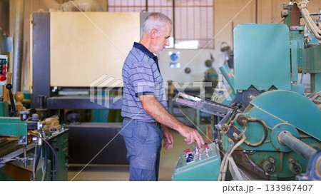 Senior worker operating woodworking machine in factory 133967407