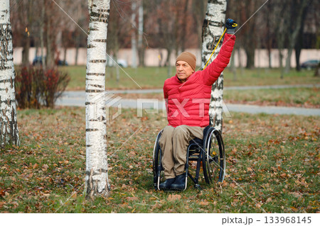 Enjoying the outdoors and exercising in a park while using a wheelchair during a sunny autumn day 133968145