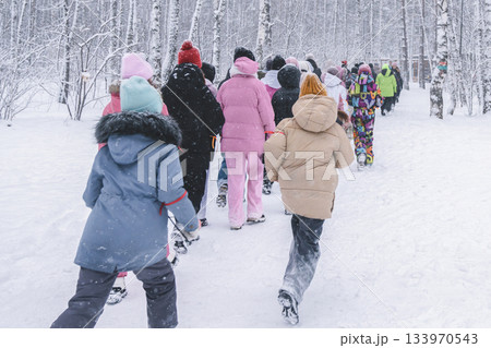 A lively group of children joyously exploring a beautiful snowcovered forest, crafting delightful winter memories A lively group of children joyously exploring a beautiful snowcovered forest, crafting delightful winter memories 133970543