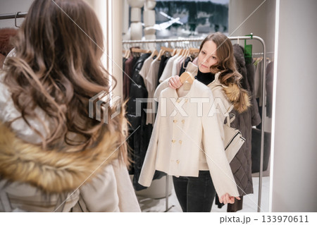 A beautiful 30-year-old white woman tries on a dress in a fashion boutique, seasonal sales A beautiful 30-year-old white woman tries on a dress in a fashion boutique, seasonal sales 133970611