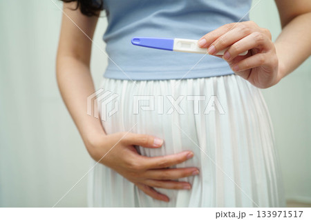 Asian holding pregnancy test for female of ovulation day, fetus, maternity, childbirth, birth control. Asian holding pregnancy test for female of ovulation day, fetus, maternity, childbirth, birth control. 133971517