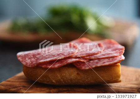 Toasted ciabatta with salami sausage on olive board Toasted ciabatta with salami sausage on olive board 133971927