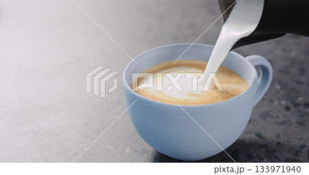 Pour steamed milk into espresso to make cappuccino in blue cup on concrete background Pour steamed milk into espresso to make cappuccino in blue cup on concrete background 133971940