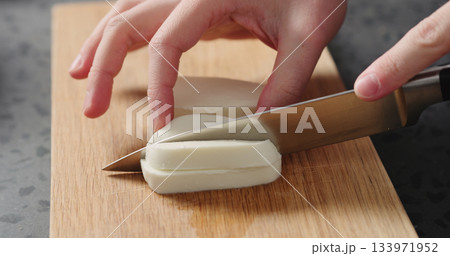 Closeup man slicing fresh mozzarella on oak board 133971952