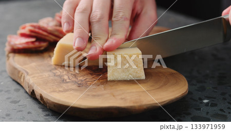 man slicing parmesan hard cheese on olive wood board 133971959