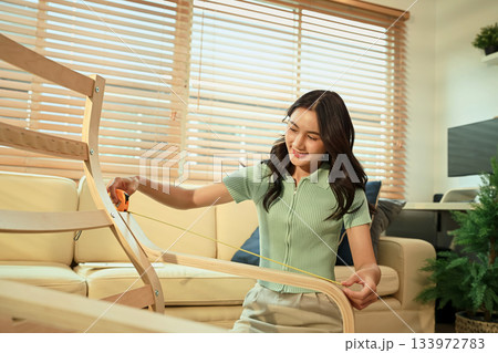 Young woman using Tape measure on a new armchair, home improvement concept Young woman using Tape measure on a new armchair, home improvement concept 133972783