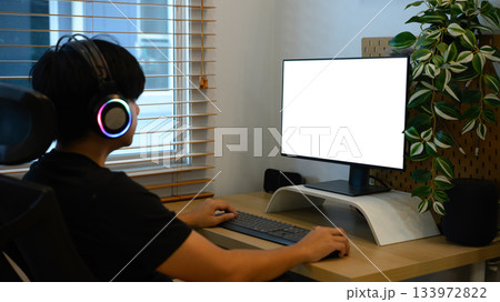 A man is using a mockup computer with empty screen on home workspace 133972822