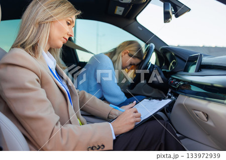 Stressed Learner Driver During Practical Exam with Instructor Taking Notes Inside Car Stressed Learner Driver During Practical Exam with Instructor Taking Notes Inside Car 133972939