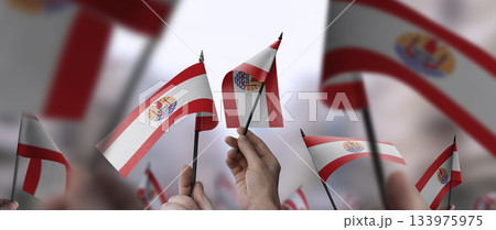 French Polynesia flags in their hands on a blurred urban background French Polynesia flags in their hands on a blurred urban background 133975975