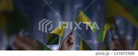 French Guiana flags in their hands on a blurred urban background 133975996