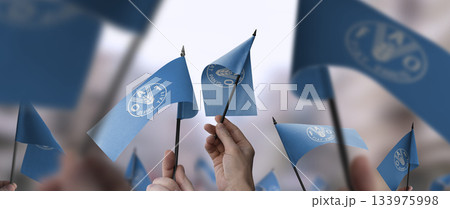 Food and agriculture organization flags in their hands on a blurred urban background 133975998