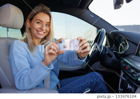 Happy New Driver Holding Fresh Driving License in Car 133976104