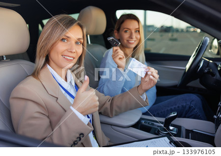 Instructor and New Driver Smiling with License After Test Instructor and New Driver Smiling with License After Test 133976105
