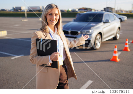 Driving Instructor Presenting Training Car and Course Cones 133976112