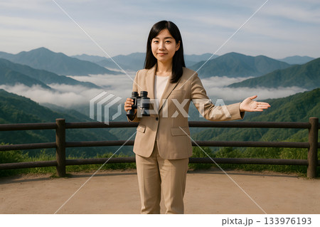 山の展望台で双眼鏡を使って案内する女性ガイド 133976193