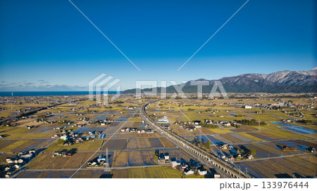 12月上旬の黒部川扇状地と北アルプスや新幹線高架橋や北陸自動車道などの風景 133976444