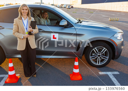 Driving Instructor Standing by Car with Learner Driver After Lesson 133976560