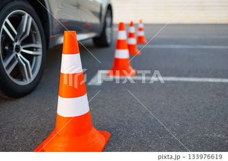 Traffic Cones Arranged in Line Near Training Car on Driving Test Area 133976619