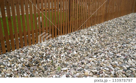 Wooden fence line with garden gravel stones 133978797