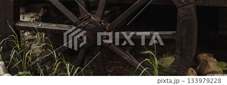 Banner old wooden wagon wheel on rustic background with stones and green grass 133979228