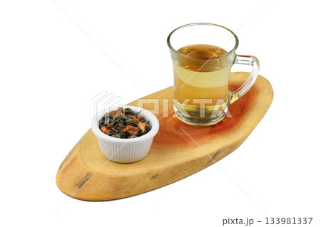 A pile of dry green tea on a white background. Apple flavor. Top view, isolated, close-up. with green tea prepared in a glass cup. 133981337