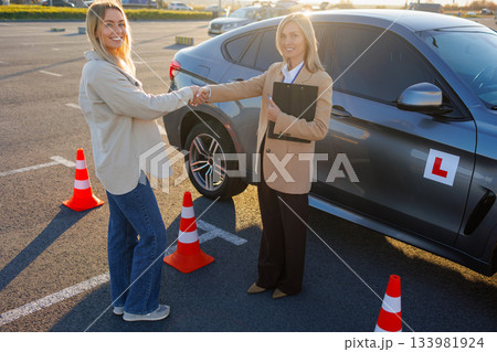 Driving School Lesson with Instructor and Student Shaking Hands Outdoors Driving School Lesson with Instructor and Student Shaking Hands Outdoors 133981924